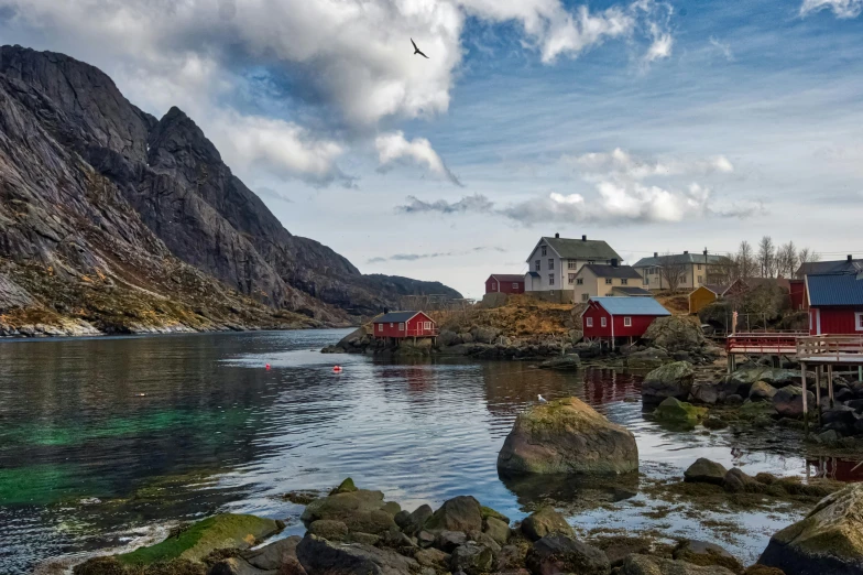 a body of water with a mountain in the background, by Harald Giersing, pexels contest winner, modernism, several cottages, lynn skordal, thumbnail, coastline