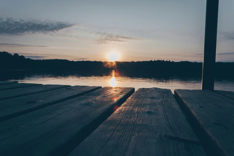 the sun is setting over a body of water, pexels contest winner, aestheticism, on a wooden table, espoo, low quality photo, clean image