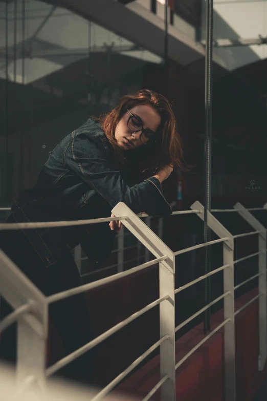 a woman leaning on a railing in front of a building, inspired by Elsa Bleda, pexels contest winner, antipodeans, girl with glasses, a redheaded young woman, androgynous male, mid night