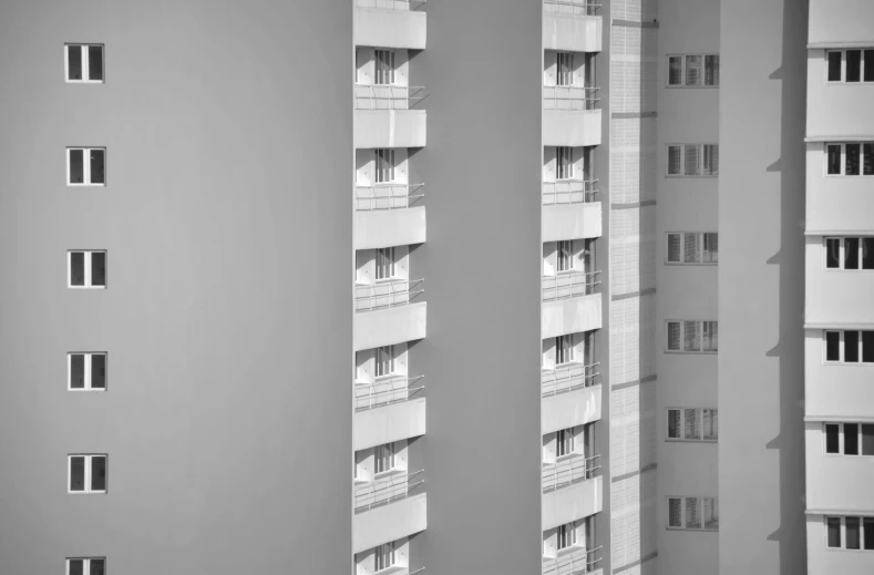 a black and white photo of a tall building, a black and white photo, inspired by Thomas Struth, pexels contest winner, brutalism, white grey color palette, balconies, no two rooms are identical. 4k, monochrome 3 d model