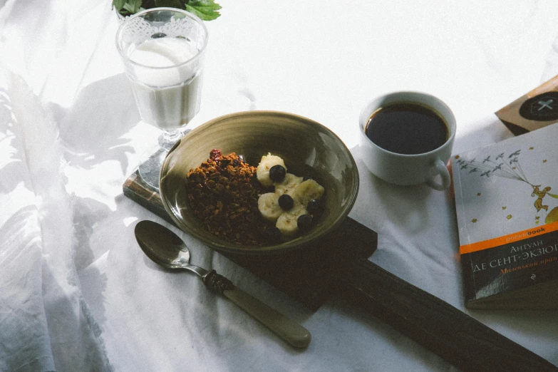 a table topped with a bowl of cereal next to a cup of coffee, a still life, pexels contest winner, background image, spoon placed, on a white table, gif