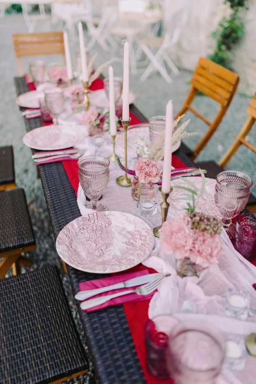 a table that has a bunch of plates on it, unsplash, renaissance, pink and red color scheme, outdoor, candles, long