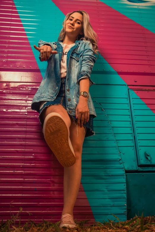 a woman standing in front of a colorful wall, trending on pexels, an aviator jacket and jorts, 15081959 21121991 01012000 4k, action pose, shows a leg