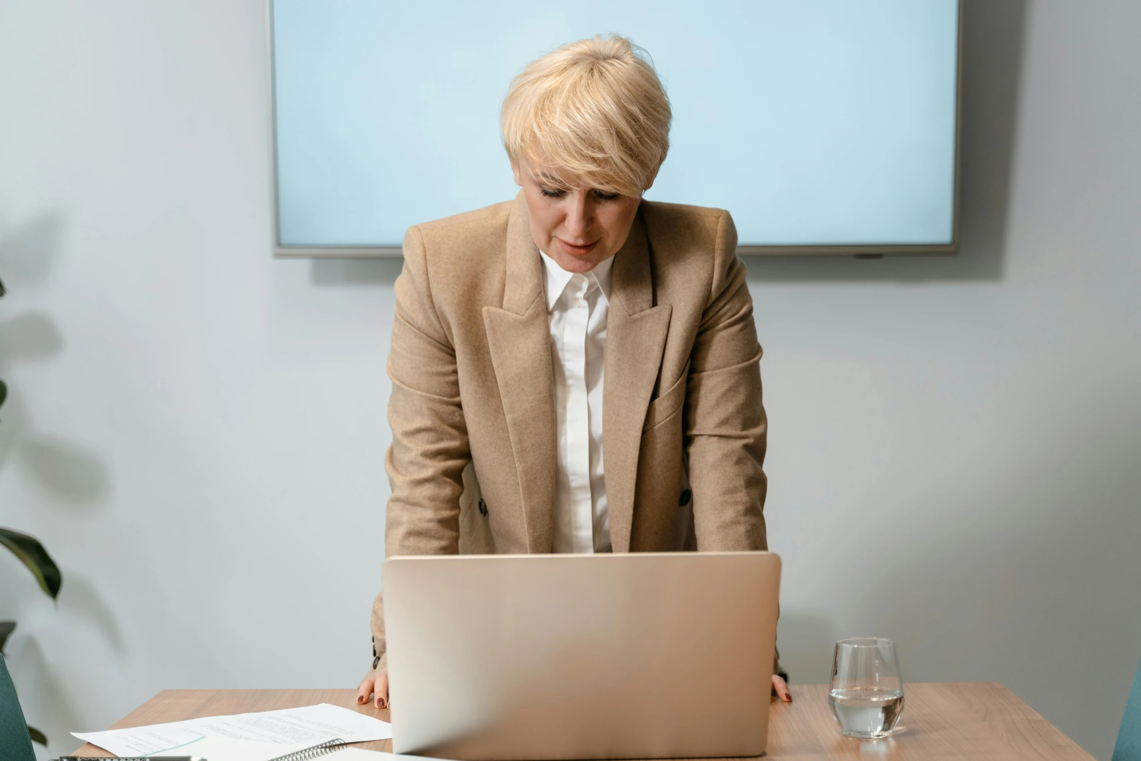 a woman sitting at a table in front of a laptop computer, by Carey Morris, pexels, renaissance, standing still, lawyer, lachlan bailey, a blond