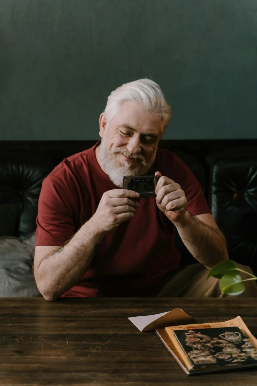 a man sitting at a table with a cup of coffee, bushy white beard, chewing on a video card, promo image, grandfatherly