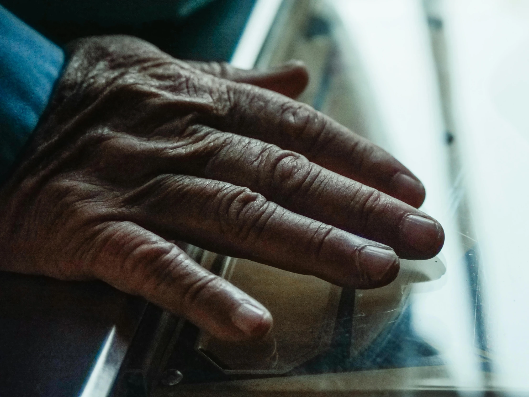 a close up of a person's hand near a window, old charismatic mechanic, sitting on a lab table, visible veins, thumbnail