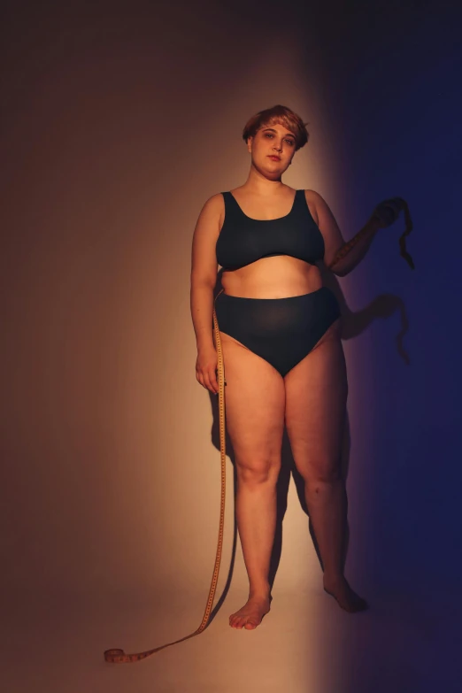 a woman in a black bikini holding a skipping rope, unsplash, renaissance, morbidly obese, colour photograph, looking sad, large tall