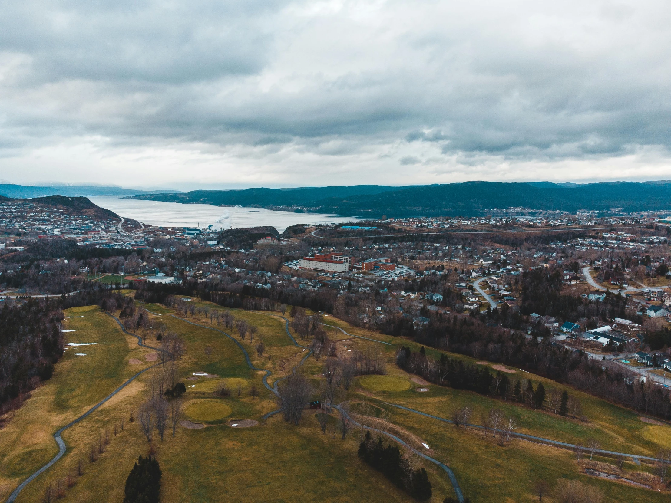 a view of a city from a bird's eye view, pexels contest winner, golf course, quebec, on a cloudy day, high quality product image”