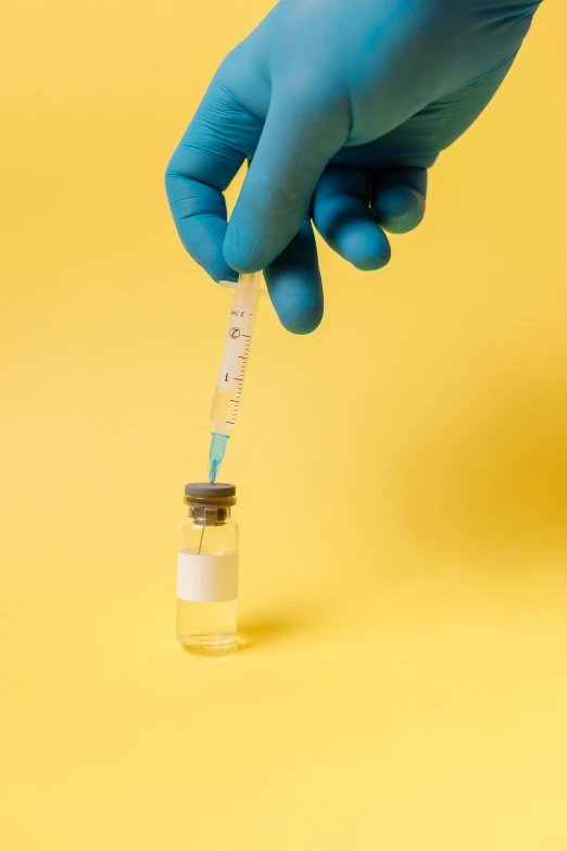 a person in a blue glove is holding a syssor, shutterstock, syringe, on a yellow canva, no cropping, ap