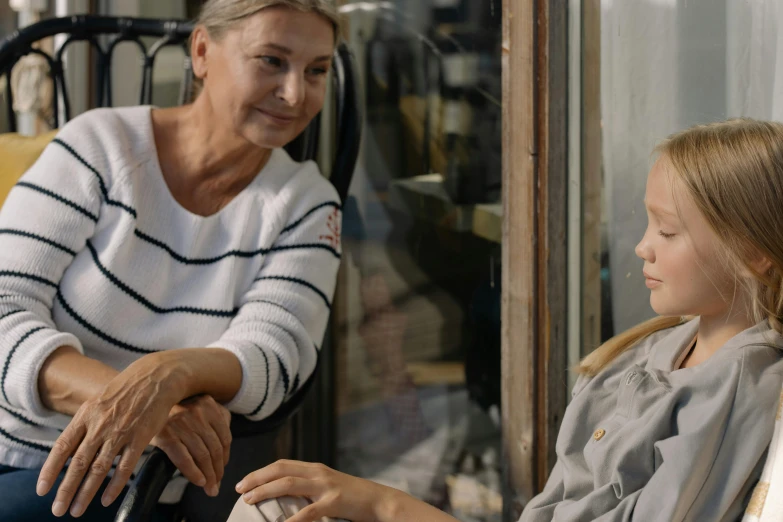 a woman sitting in a chair next to a little girl, pexels contest winner, looking outside, older woman, 15081959 21121991 01012000 4k, realistic »