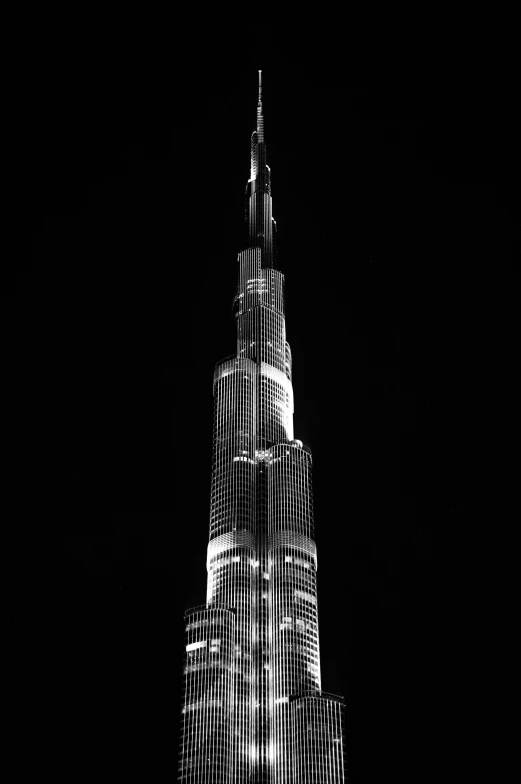 a very tall building lit up at night, a black and white photo, pexels contest winner, hurufiyya, dubai, a creature 5 meters tall, spire, night photo