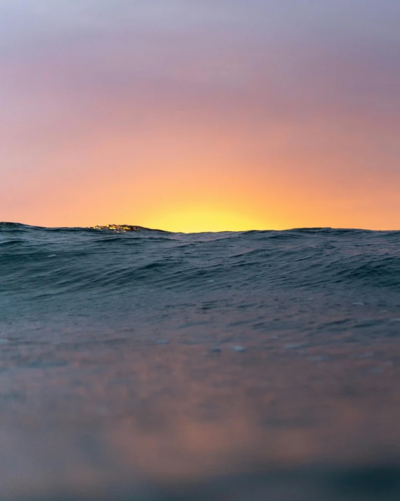 a man riding a wave on top of a surfboard, by Jacob Toorenvliet, unsplash contest winner, minimalism, large twin sunset, photo of the middle of the ocean, waves of lights, looking sad