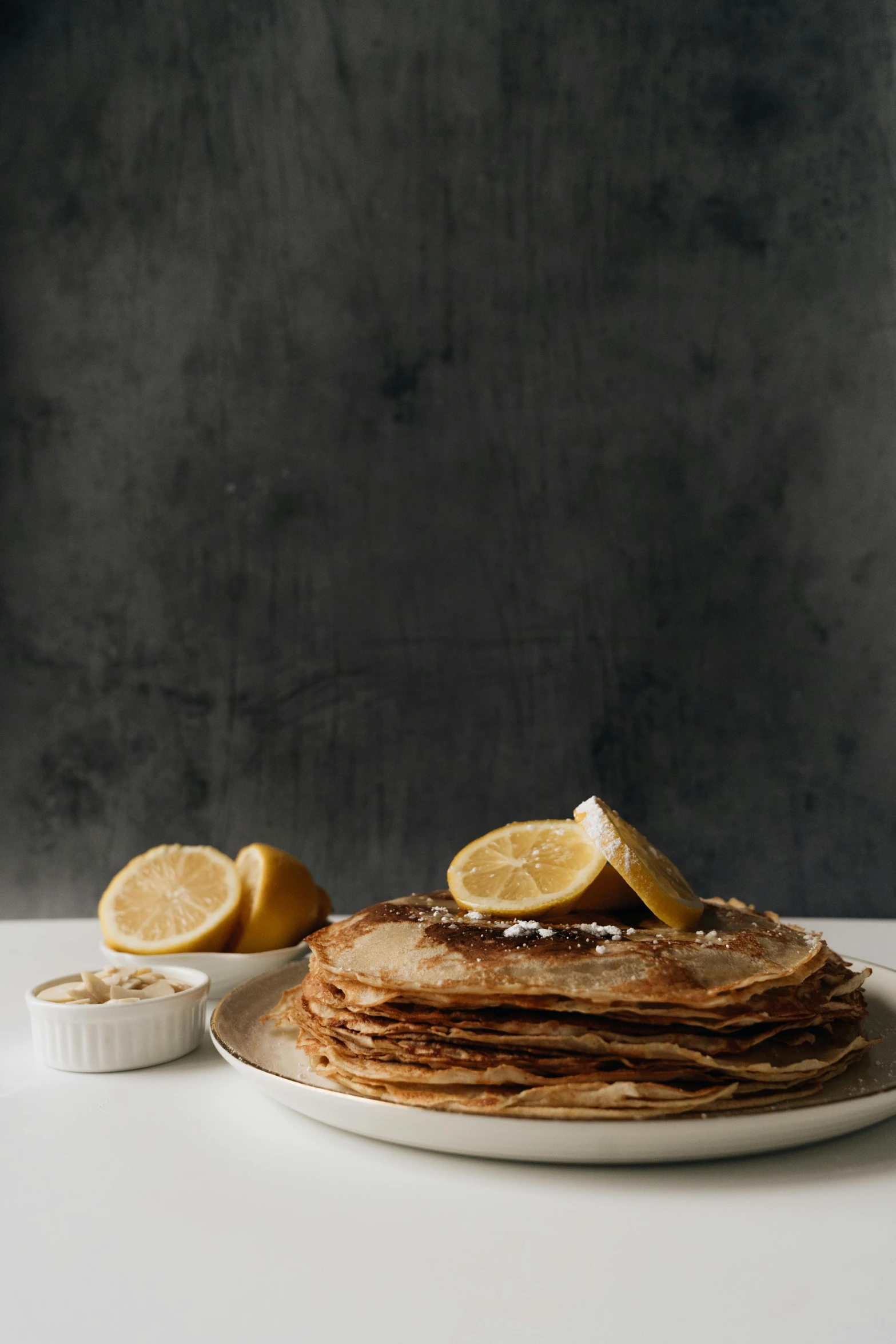 a stack of pancakes sitting on top of a white plate, by Lee Loughridge, renaissance, lemon, folded, humus, still life photo of a backdrop