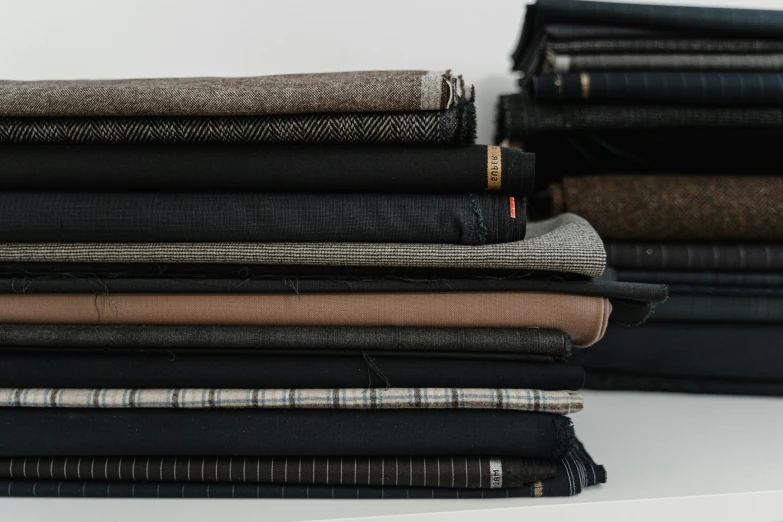 a stack of jeans sitting on top of a table, black fine lines on warm brown, mesh fabrics, charcoal and champagne, creterion collection