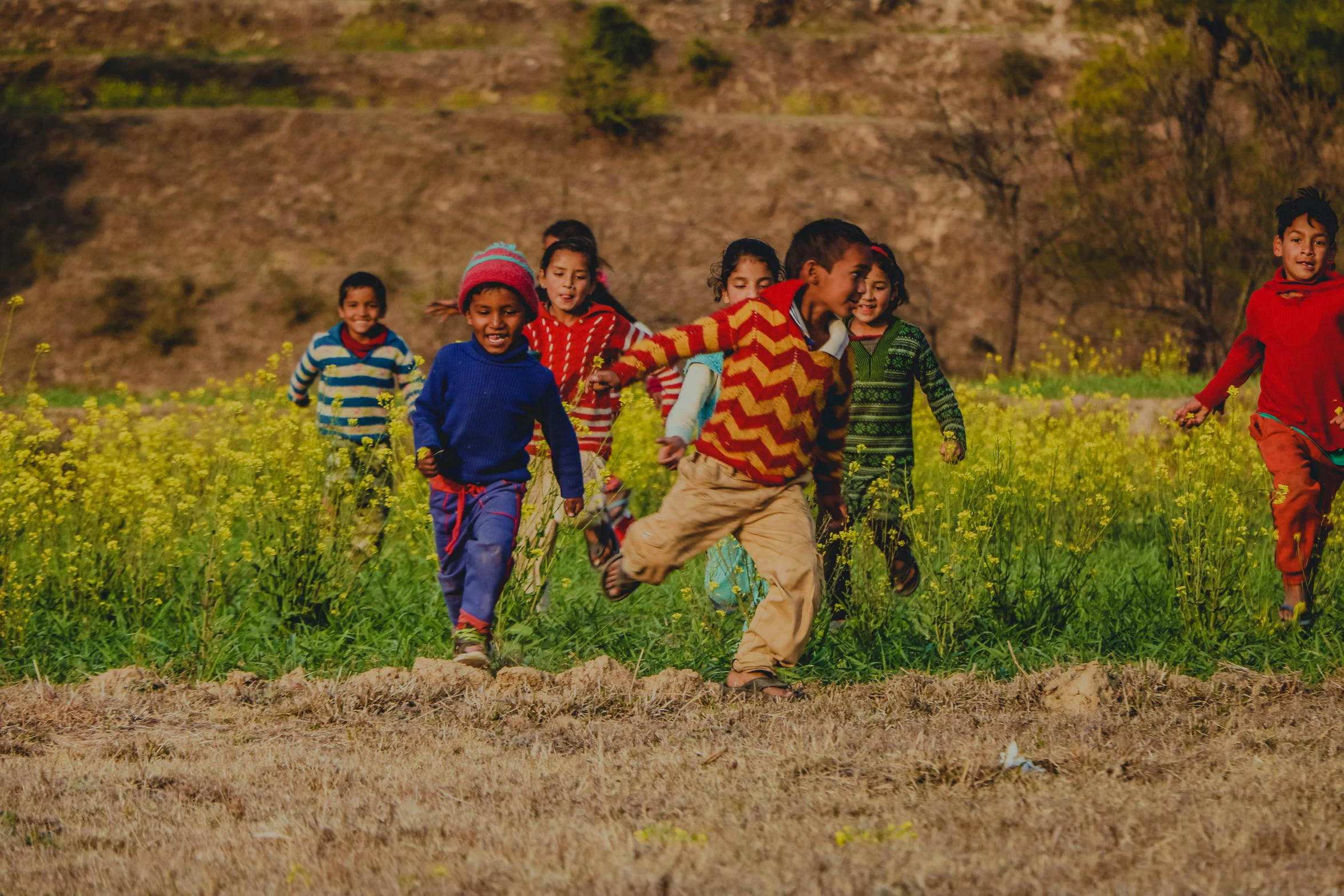 a group of children running through a field, pexels contest winner, nepal, thumbnail, warm spring, coloured