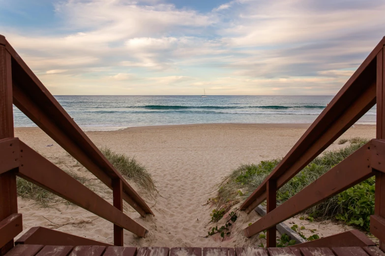 a view of the beach from a set of stairs, by Peter Churcher, unsplash, “ iron bark, sunset beach, dune, a wooden