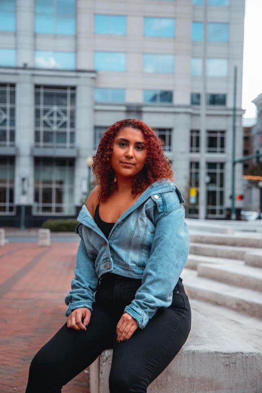 a woman sitting on a bench in front of a building, by Washington Allston, trending on pexels, renaissance, wearing a jeans jackets, plus-sized, riyahd cassiem, high quality image