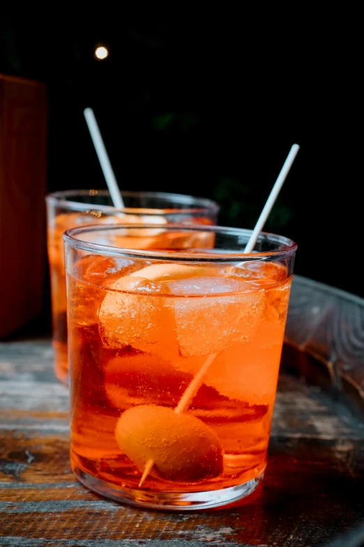 a close up of a drink in a glass on a table, thumbnail, large cornicione, orange rocks, naples