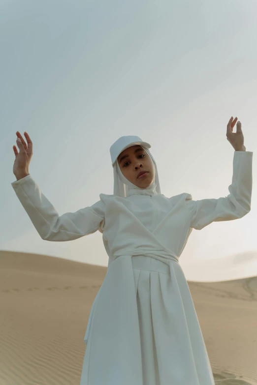 a woman in a white dress standing in the desert, an album cover, inspired by Modest Urgell, billie eilish as a nun, ashteroth, ( ( theatrical ) ), wearing a white bathing cap