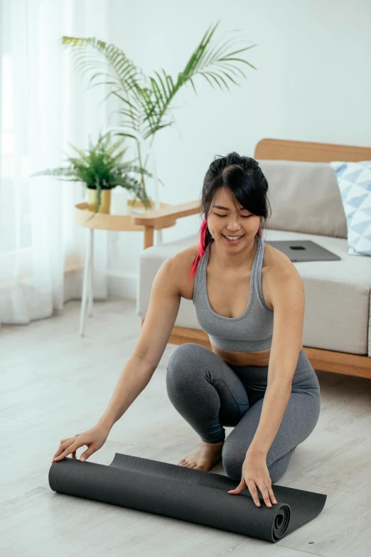 a woman sitting on the floor with a yoga mat, pexels contest winner, holography, lifting weights, looking at monitor, an asian woman, slate