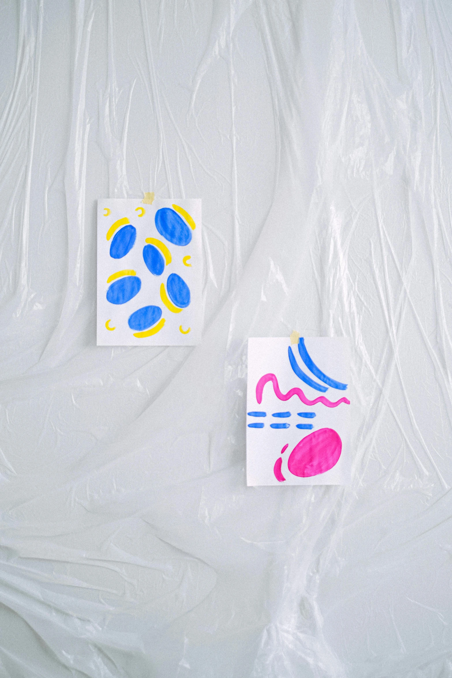 a couple of paintings sitting on top of a white sheet, a screenprint, by Harvey Quaytman, unsplash, translucent eggs, playful and cheerful, dressed in plastic bags, ilustration