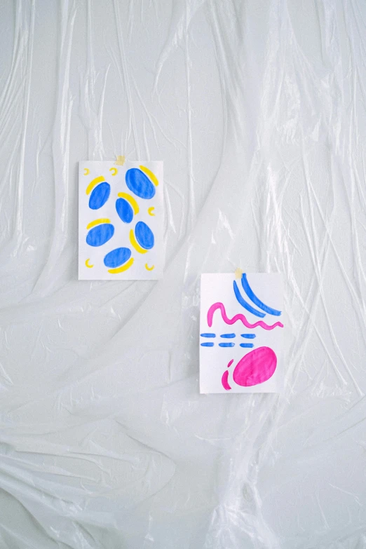 a couple of paintings sitting on top of a white sheet, a screenprint, by Harvey Quaytman, unsplash, translucent eggs, playful and cheerful, dressed in plastic bags, ilustration