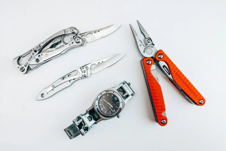 a group of tools sitting on top of a white surface, by Alexander Fedosav, pexels, hyperrealism, breitling, a folding knife, 🦩🪐🐞👩🏻🦳, stainless steel