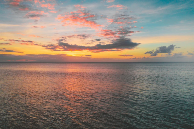 a large body of water with a sunset in the background, pexels contest winner, great barrier reef, pink clouds, drone footage, multicoloured