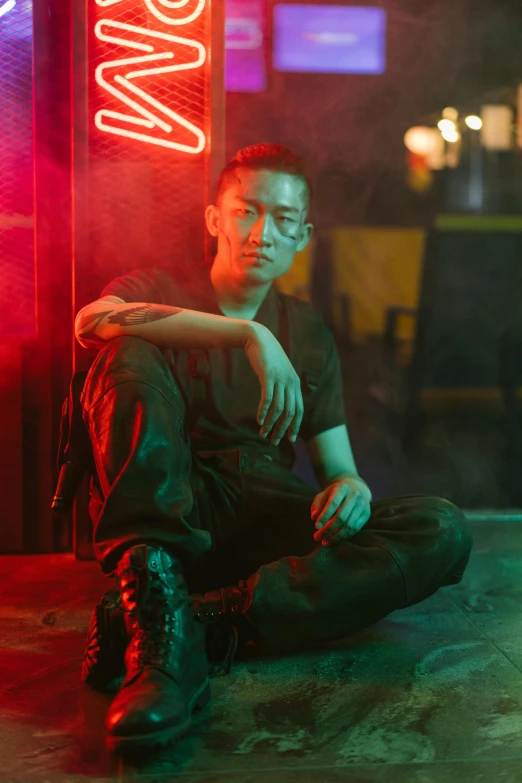 a man sitting on the ground in front of a neon sign, inspired by Liam Wong, an epic non - binary model, joe taslim, profile image, military composure