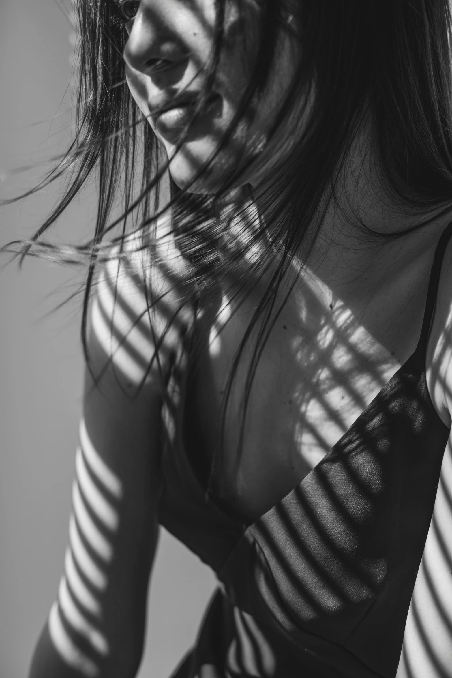 a black and white photo of a woman with long hair, inspired by Max Dupain, unsplash contest winner, sunlight filtering through skin, wearing bra, striped, bralette