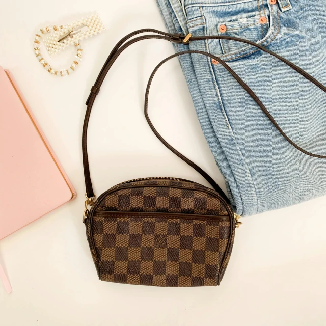 a purse sitting on top of a table next to a notebook, by Dan Luvisi, trending on pexels, renaissance, checkered pattern, 🎀 🗡 🍓 🧚, brown, streetwear