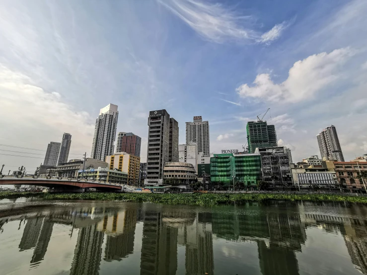 a large body of water surrounded by tall buildings, by Basuki Abdullah, pexels contest winner, hyperrealism, building along a river, 1970s philippines, paisley, glass buildings