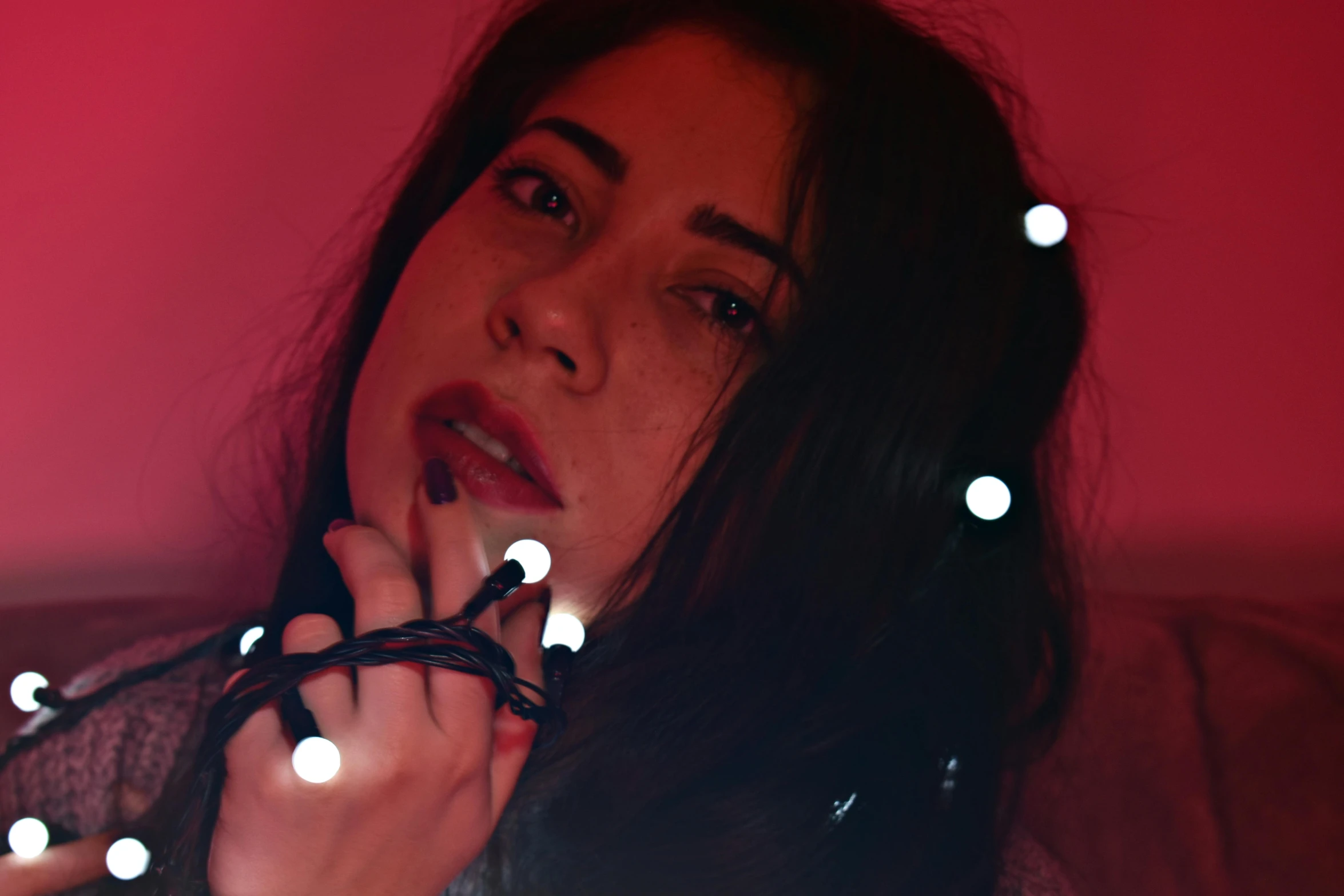 a close up of a person holding a string of lights, an album cover, inspired by Elsa Bleda, pexels contest winner, serial art, charli xcx, red lighting on their faces, press shot, blanca alvarez