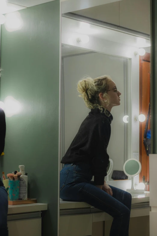 a woman sitting on a counter in front of a mirror, inspired by Nan Goldin, trending on unsplash, photorealism, julia garner, panoramic shot, full body profile, high angle