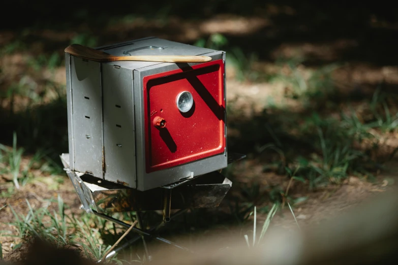 a small stove sitting on top of a grass covered field, unsplash, cubo-futurism, red mechanical body, loot box, ignant, pixvy