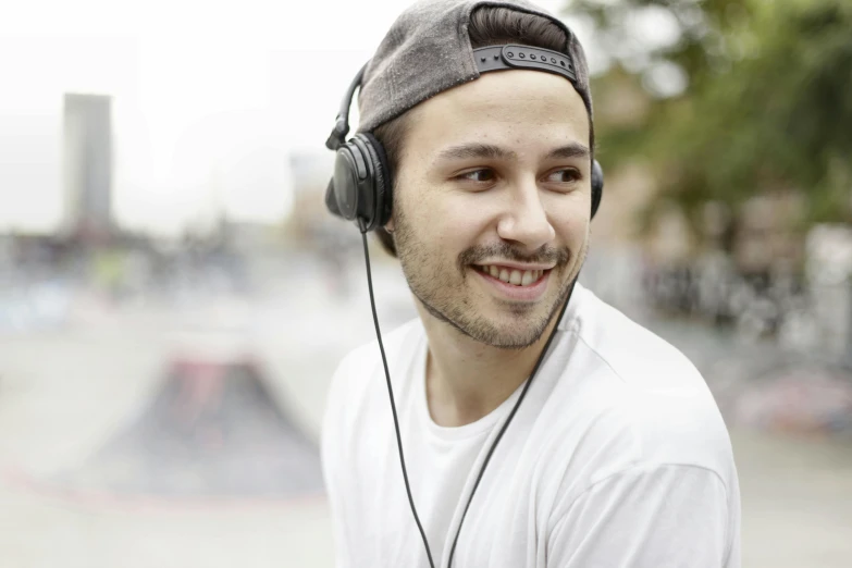 a man wearing headphones in a skate park, inspired by Niko Henrichon, smiling male, profile image, fan favorite, bronze headset