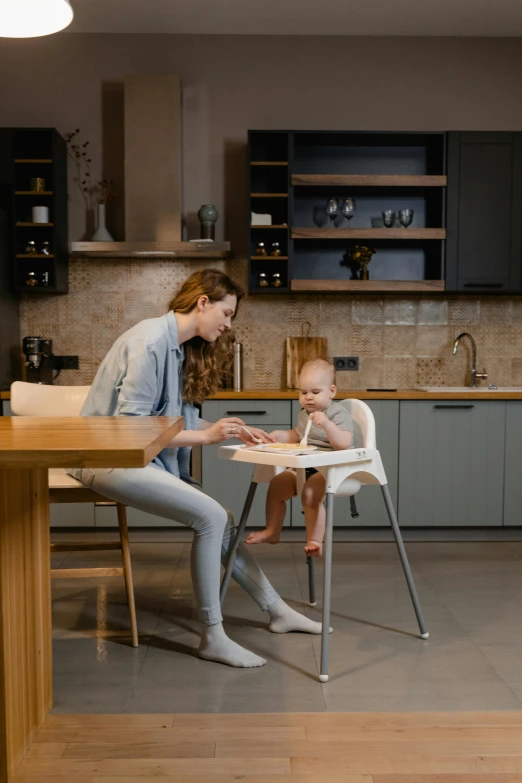 a woman sitting at a table with a baby in a high chair, sleek design, professionally assembled, thumbnail, easygoing