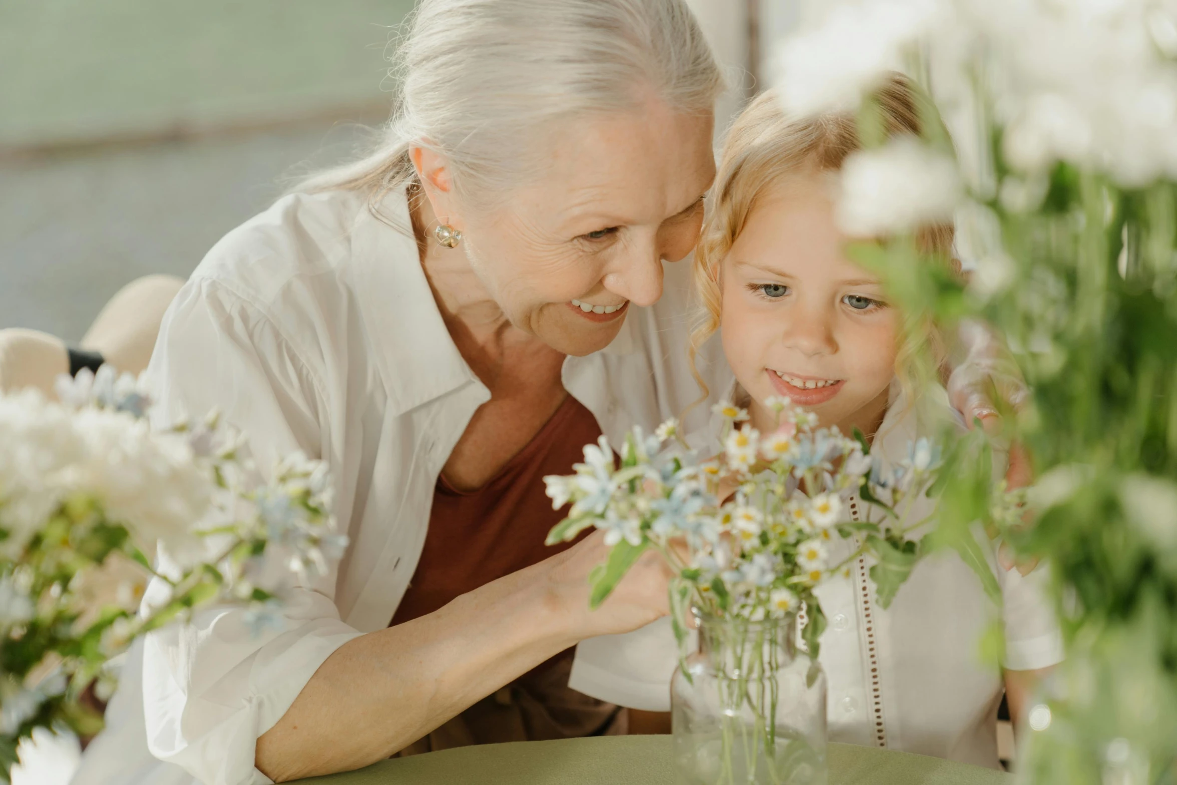 a woman and a little girl sitting at a table, pexels contest winner, carrying flowers, white-haired, local conspirologist, youtube thumbnail