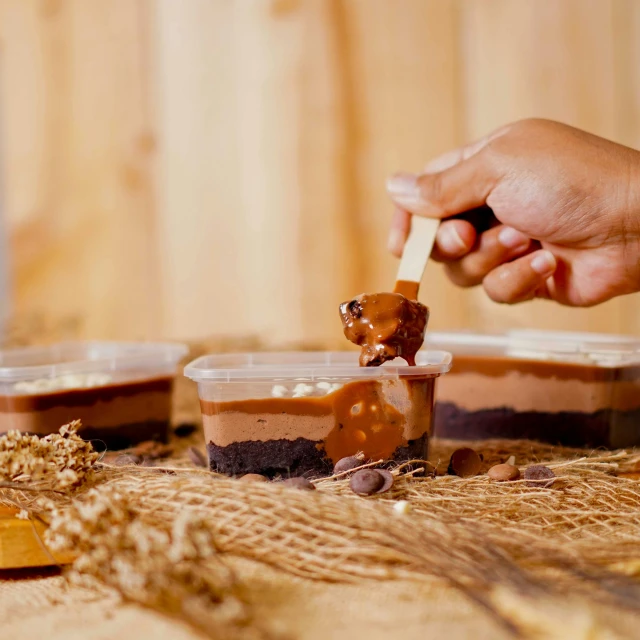 a person dipping something into a bowl of food, an album cover, by Julia Pishtar, pexels contest winner, jakarta, chocolate frosting, caramel, humus