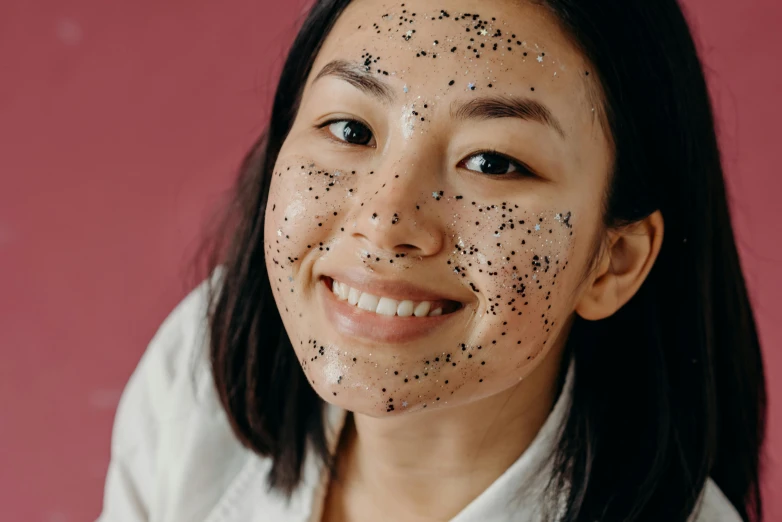 a woman with sprinkles on her face, a stipple, trending on pexels, mingei, charcoal skin, manuka, asian female, long chin