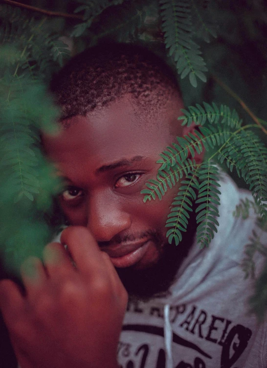 a close up of a person holding a plant, an album cover, inspired by Chinwe Chukwuogo-Roy, pexels contest winner, realism, attractive man, friendly eyes, lush surroundings, avatar image