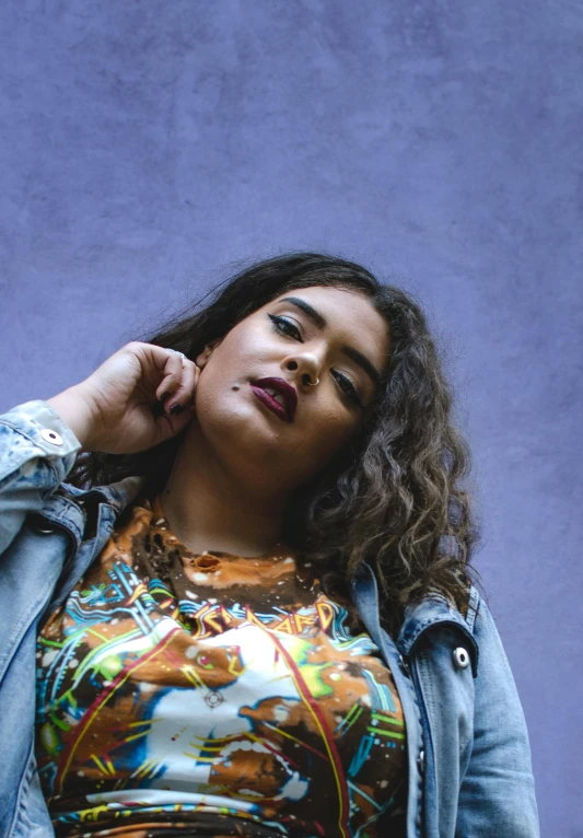 a woman standing in front of a blue wall, an album cover, trending on pexels, graffiti, alluring plus sized model, violet myers, curly haired, large)}]