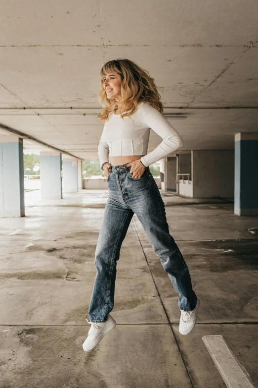 a woman jumping in the air in a parking garage, an album cover, inspired by Jean Hey, trending on pexels, jeans pants, imogen poots, portrait full body, midriff