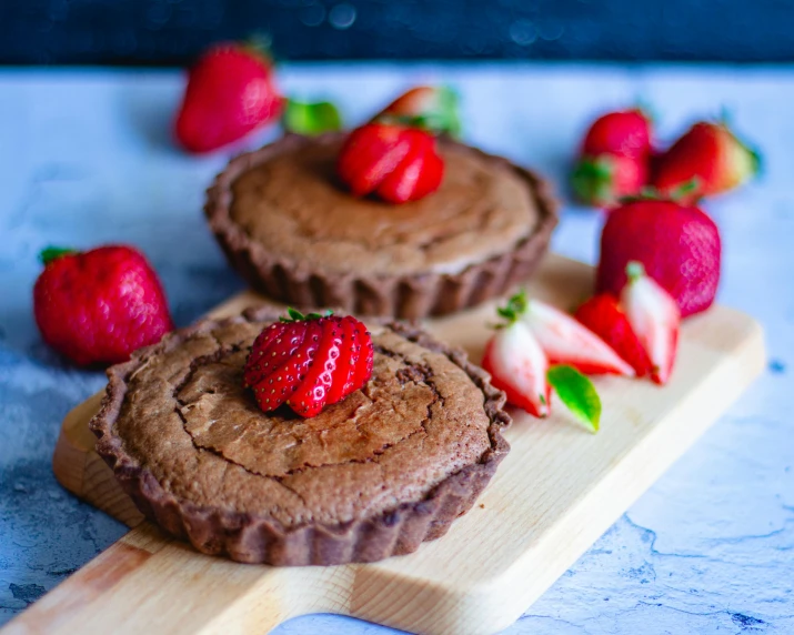 a couple of desserts sitting on top of a wooden cutting board, profile image