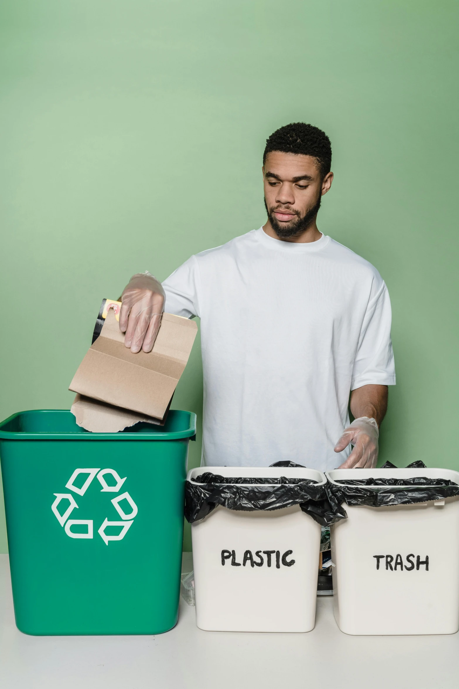 a man standing in front of three recycling bins, trending on pexels, plasticien, green and brown clothes, avatar image, made of paper, repairing the other one