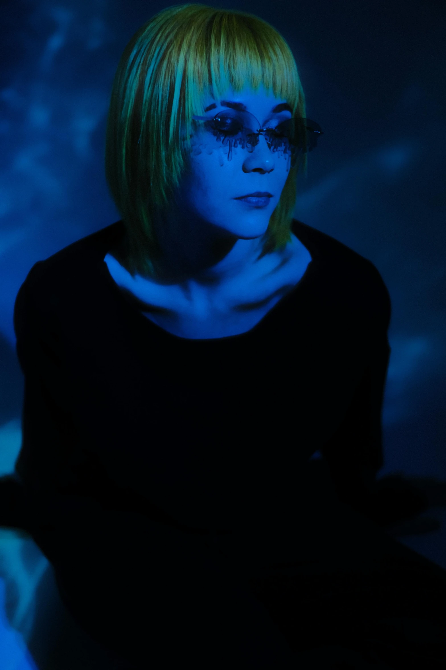 a woman sitting in front of a blue light, bubble goth, bleached colours, with a bob cut, press shot