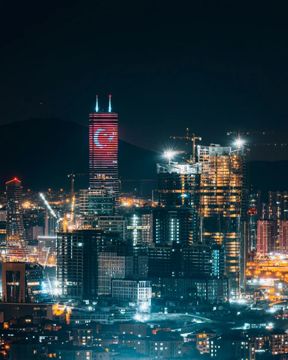 a view of a city at night from the top of a hill, a colorized photo, pexels contest winner, hurufiyya, tall building, banner, red building, turkey