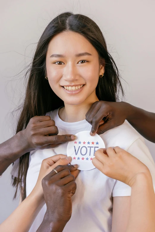 a woman putting a vote on another woman's shirt, by Zeen Chin, pexels contest winner, renaissance, young woman's face, stickers, beauty campaign, mei-ling zhou