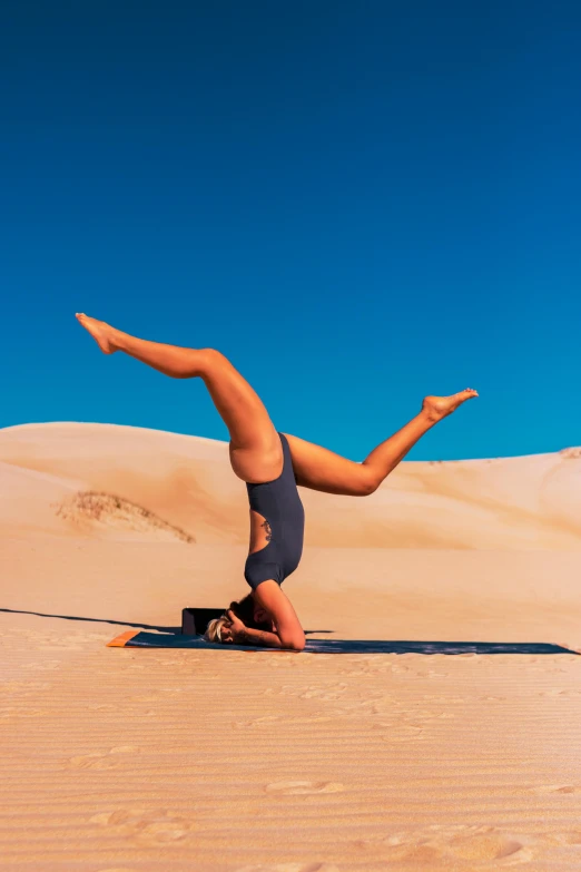 a man doing a handstand in the desert, unsplash, arabesque, australia, a woman floats in midair, laying on sand, slightly tanned