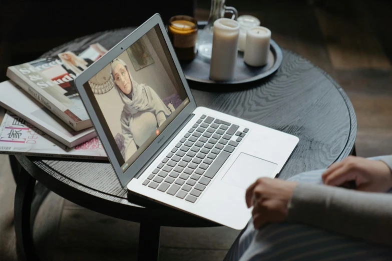 a person sitting at a table with a laptop, by Julia Pishtar, pexels contest winner, hurufiyya, shabab alizadeh, webcam, serena malyon, displayed